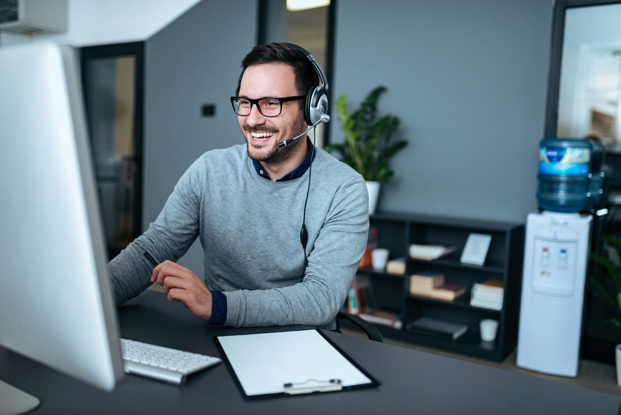 Portrait of a handsome smiling man with headset working on the c